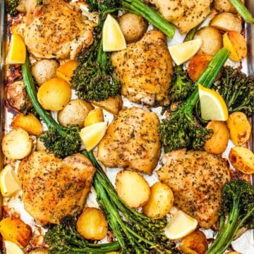 overhead image of a sheet pan with chicken thighs, potatoes, and broccoli.