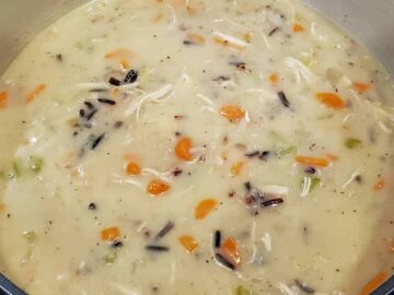 Image shows the soup after adding the chicken broth, mil, rice, and chicken being simmered until slightly thickened.