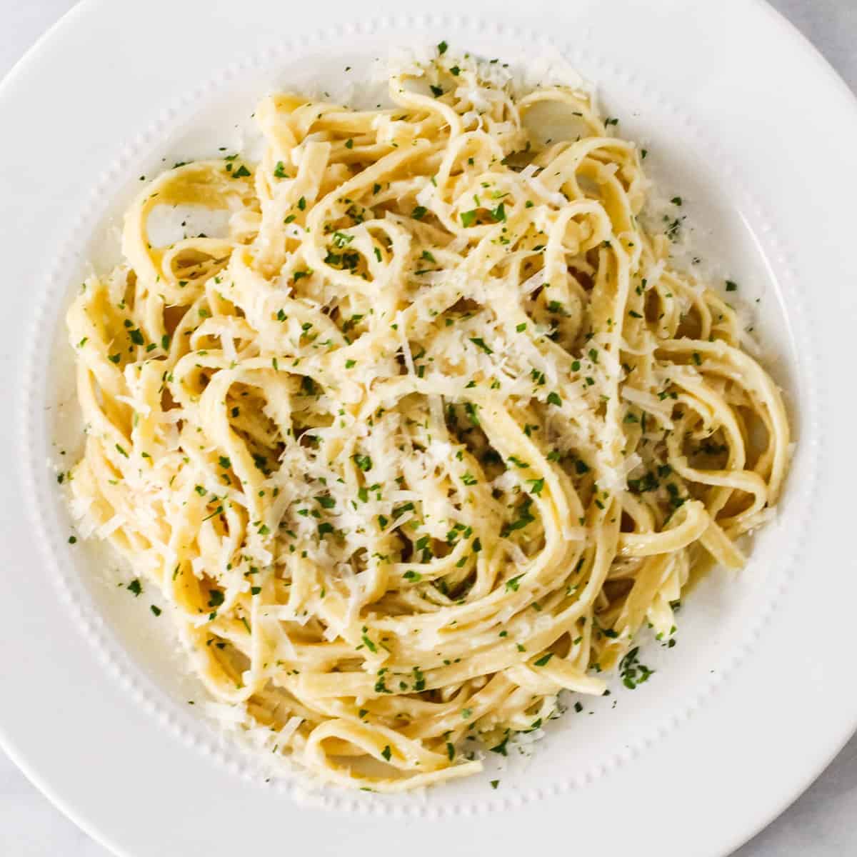 Overhead image of a serving of fettuccine tossed in a creamy homemade alfredo sauce.