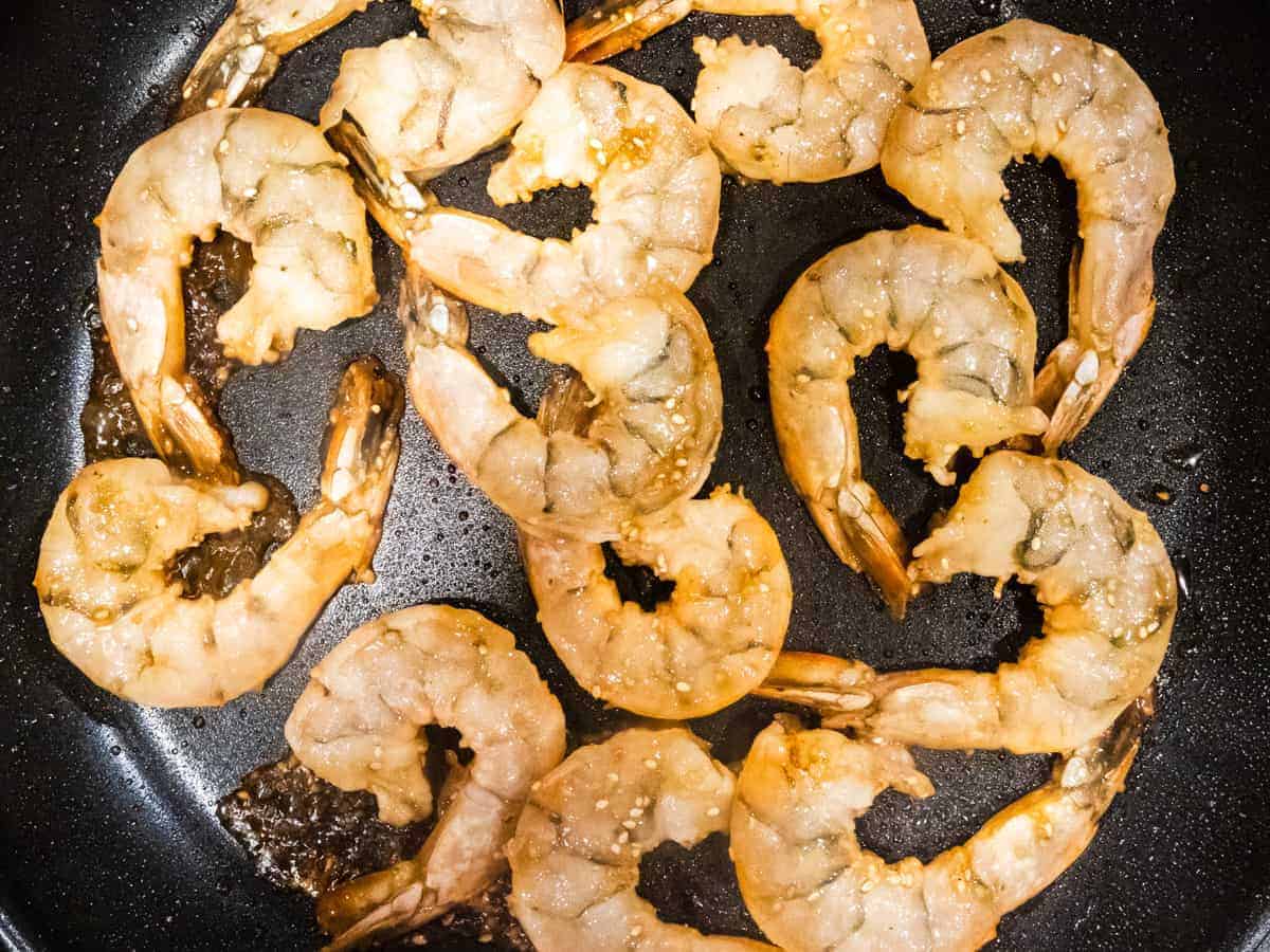 Shrimp being sautéed in a pan.