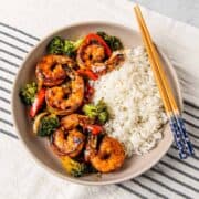 Overhead view of a bowl of honey garlic shrimp stir fry served with steamed rice.