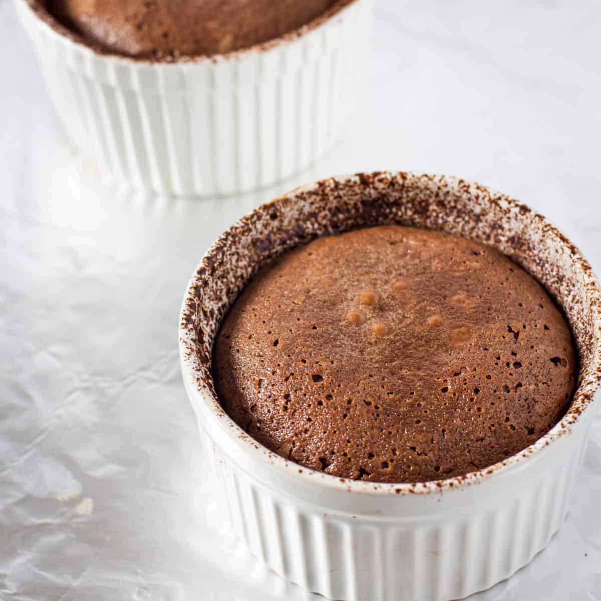 Baked molten chocolate lava cake shown cooling in a ramekin before serving.