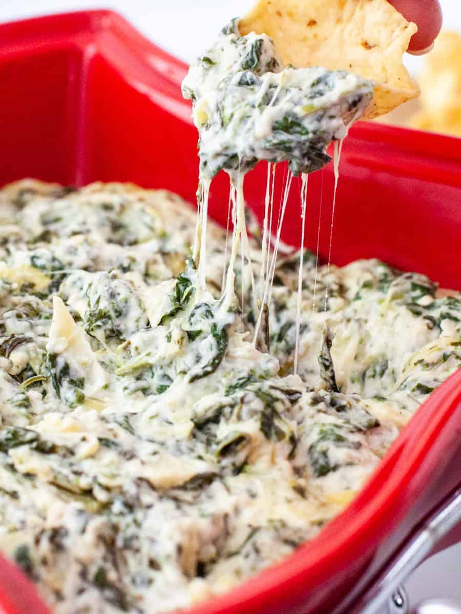 Easy cheesy spinach artichoke dip served in a baking dish with tortilla chips.