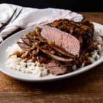 London broil shown on a bed of rice topped with mushroom and onion gravy.