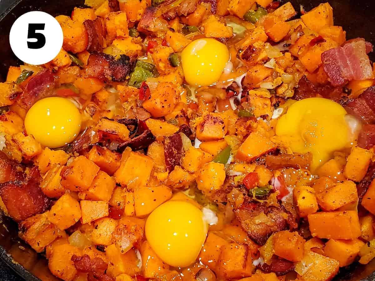 Bacon added back to the sweet potato hash with fresh cracked eggs overtop.