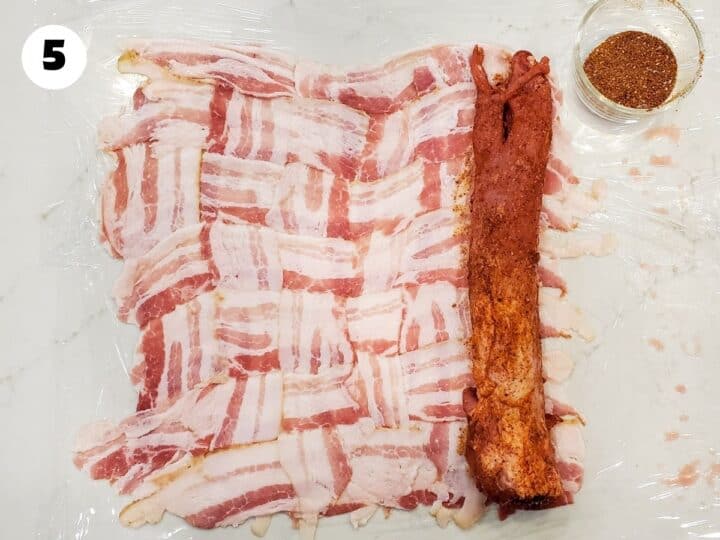 Seasoned pork tenderloin shown set at one end of the weaved bacon.