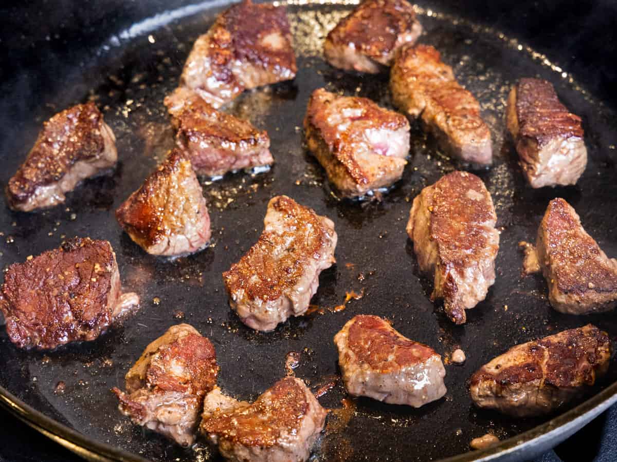 Beef tenderloin tips being sauteed in a cast iron skillet.