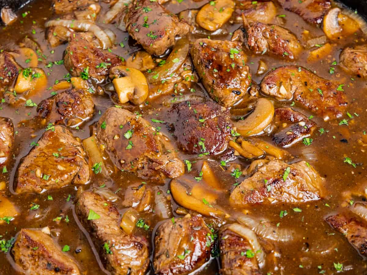 Close up image of the beef tips and mushroom gravy in a skillet. 