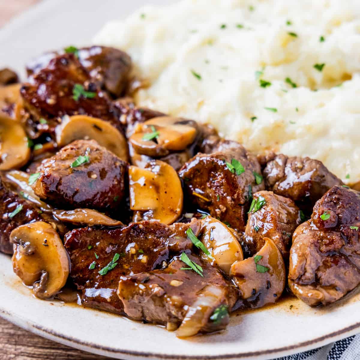 Close up view of seared tenderloin tips covered in mushroom gravy.