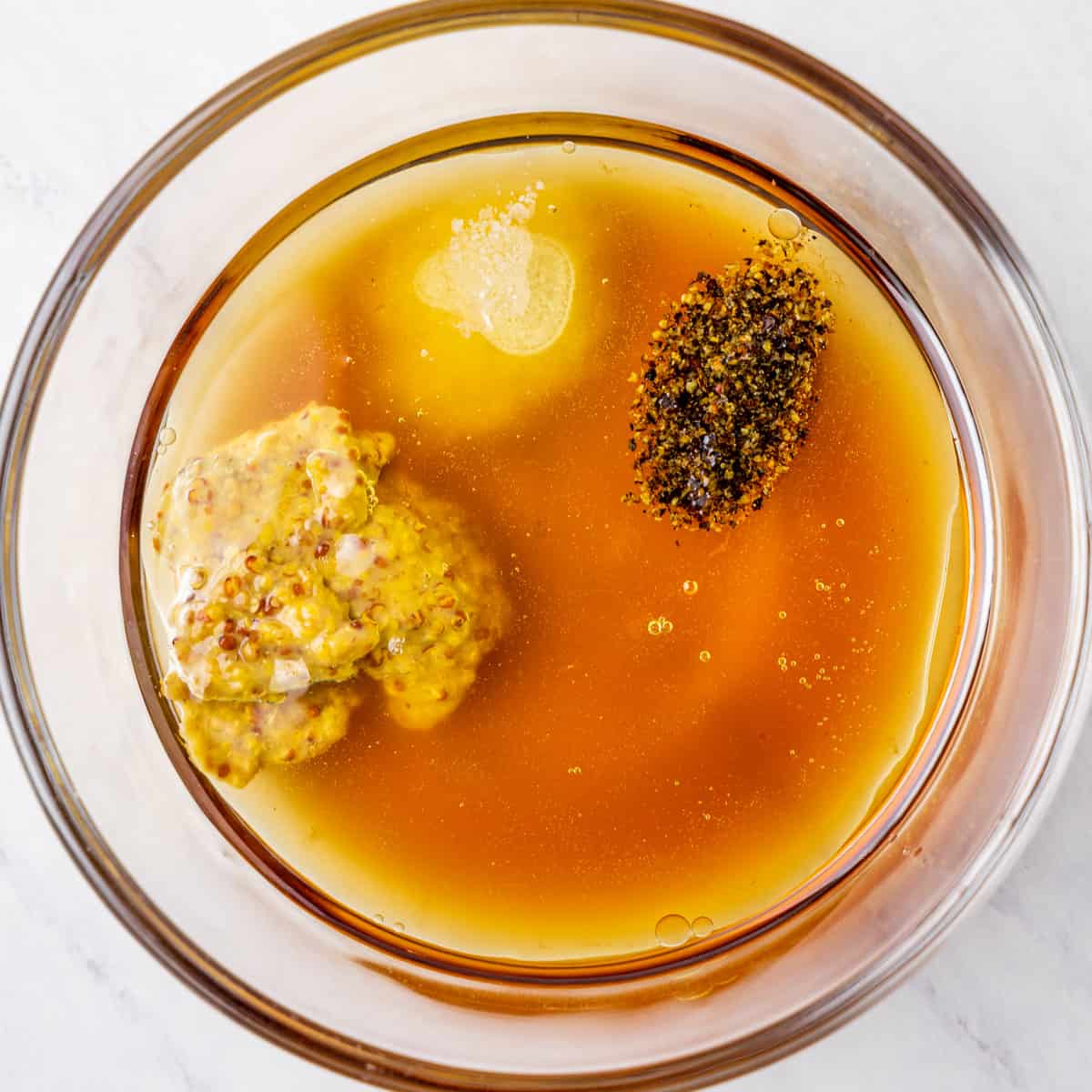 Ingredients for maple dijon vinaigrette dressing shown in a mixing bowl before combining.