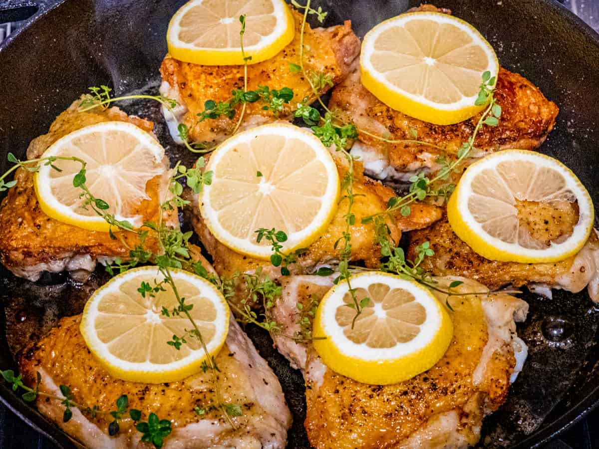 Chicken topped with lemon and thyme before being oven baked in a skillet. 