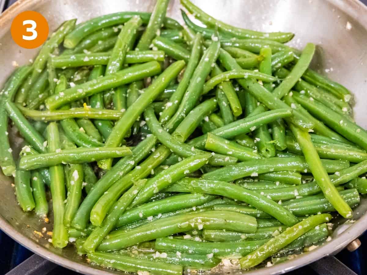 Green beans with garlic butter cooking in a pan.