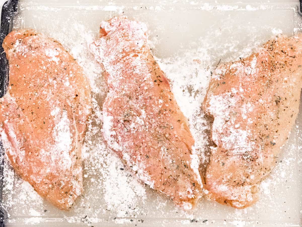 Chicken breasts shown after seasoning and coating with flour.