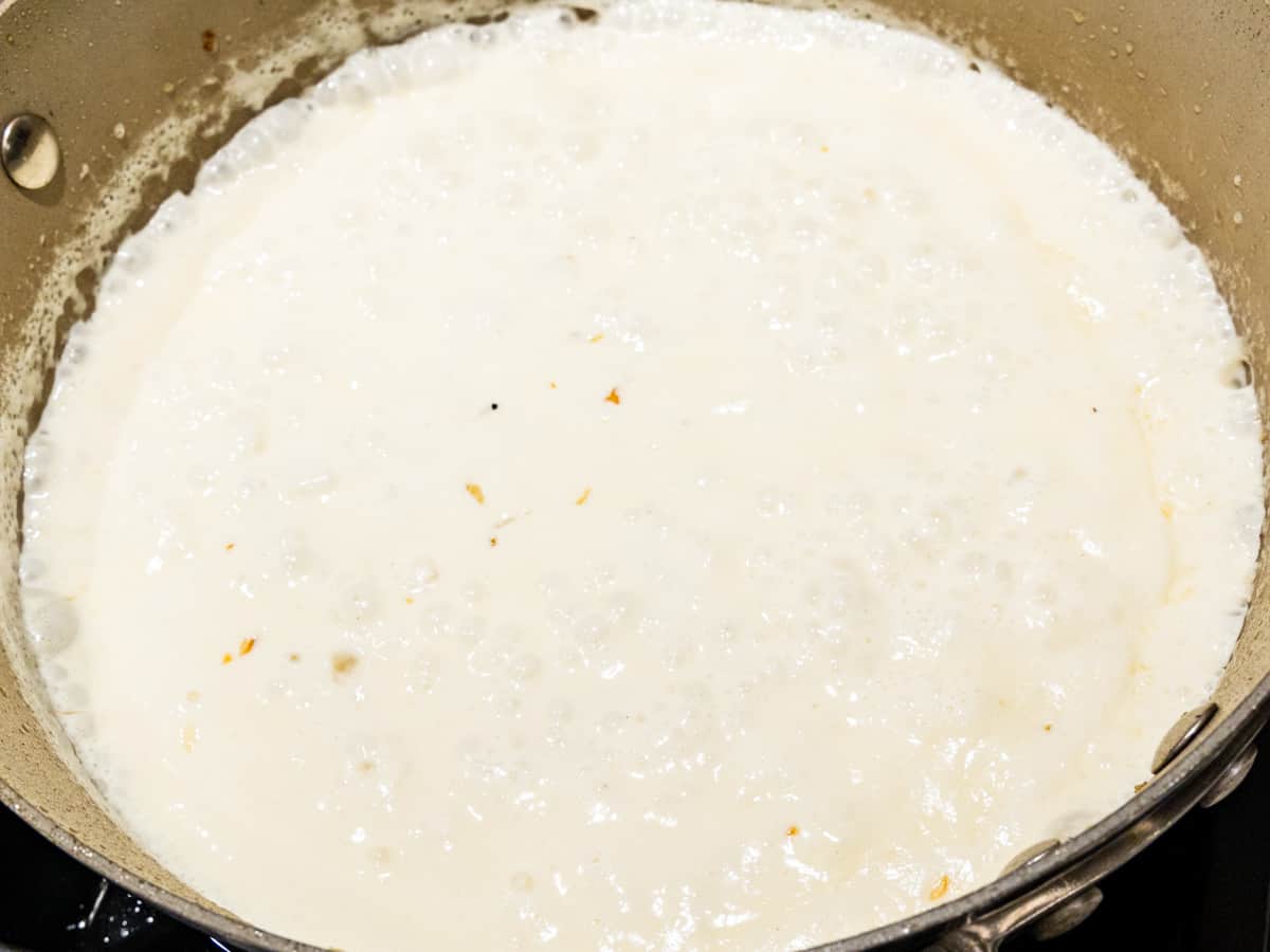 Garlic parmesan cream sauce shown simmering in a skillet.