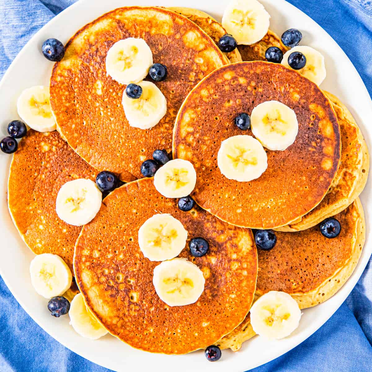 Overhead of a plate of oatmeal banana pancakes topped with blueberries and sliced banana.