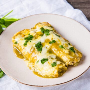Chicken enchiladas with green sauce served on a plate.