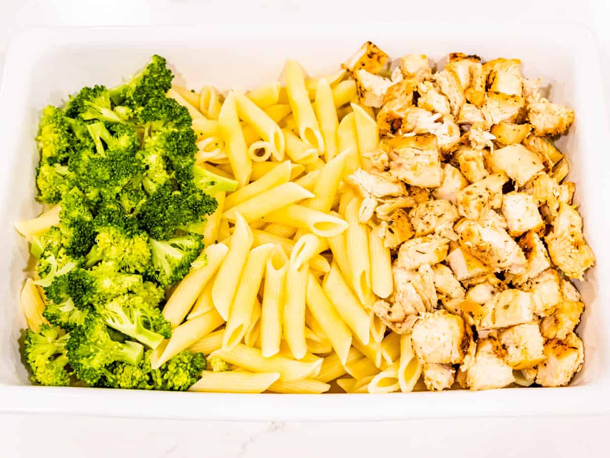 Cooked chicken, pasta, and broccoli shown in a casserole dish.