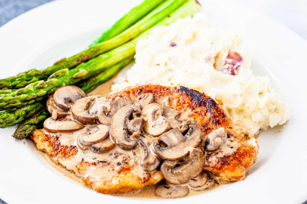 A serving of chicken marsala, topped with mushrooms and creamy marsala sauce.