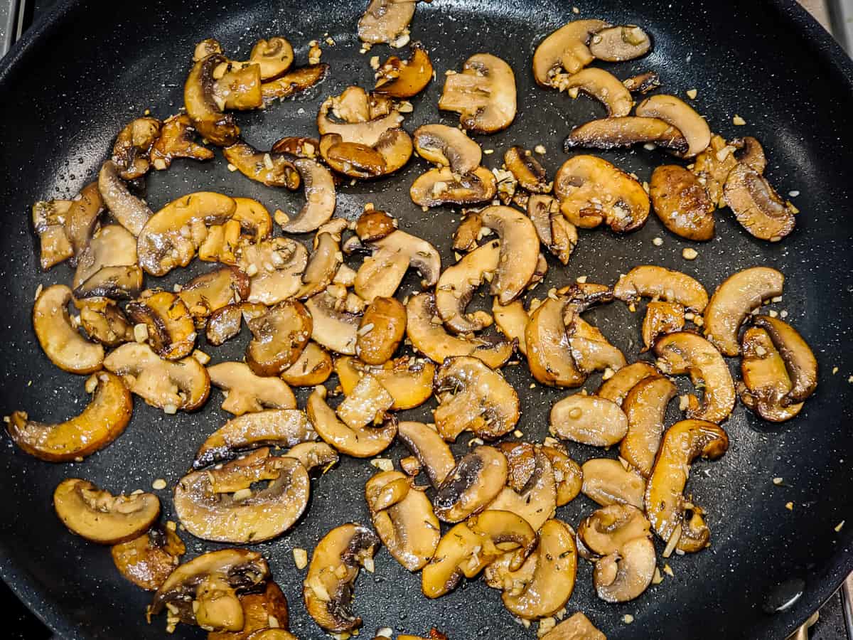 Mushrooms cooking in a skillet.