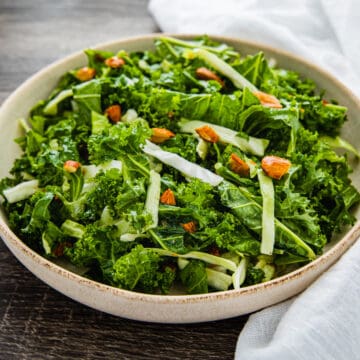 Side angle view of a bowl of kale salad with maple dijon vinaigrette.