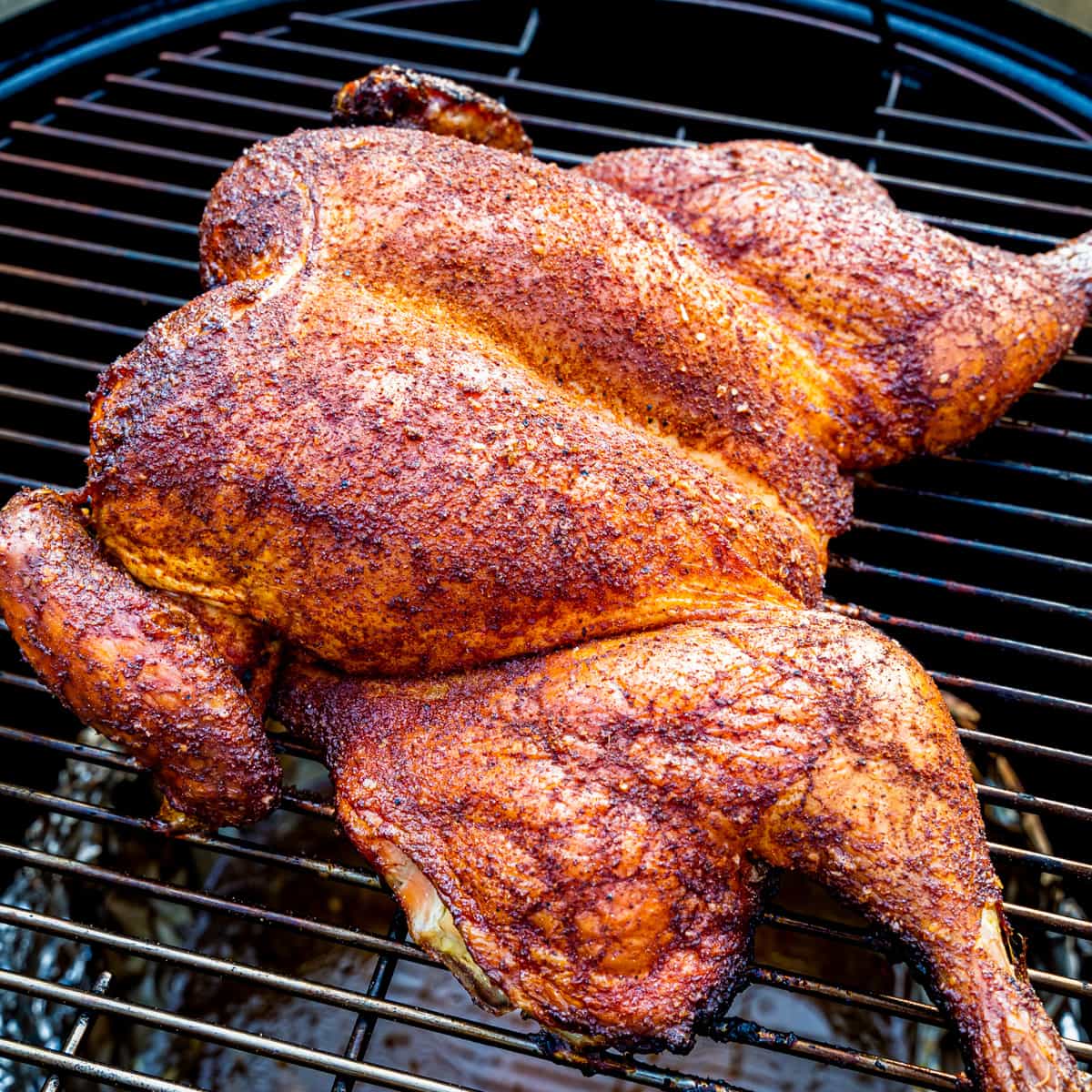 A spatchcocked chicken cooking on a smoker.