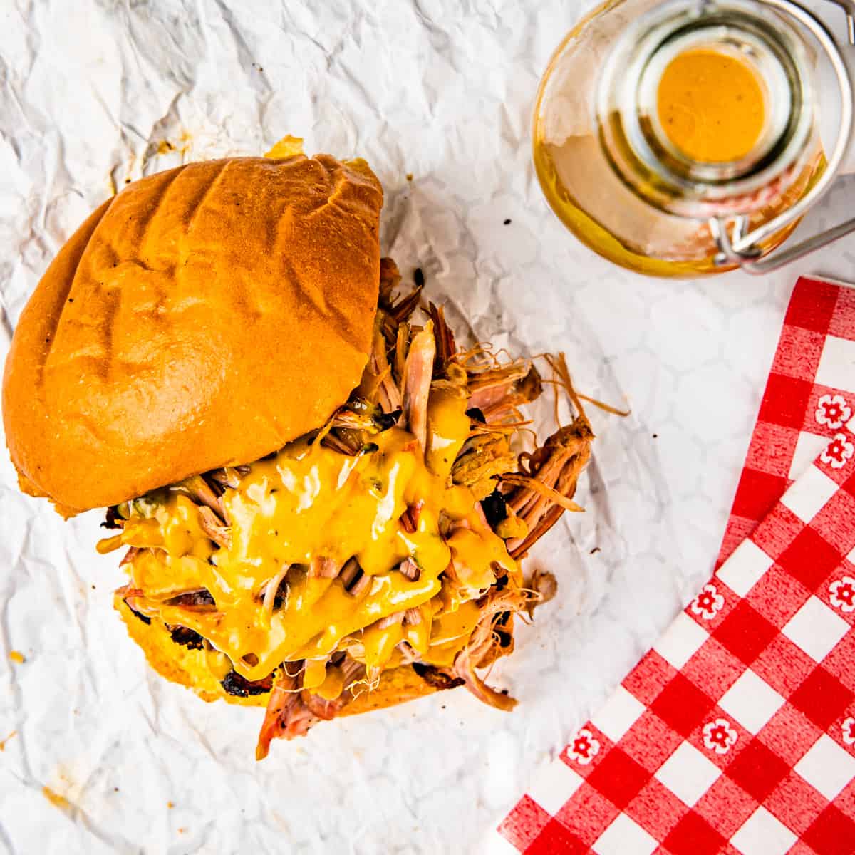 A pulled pork sandwich topped with golden bbq sauce.