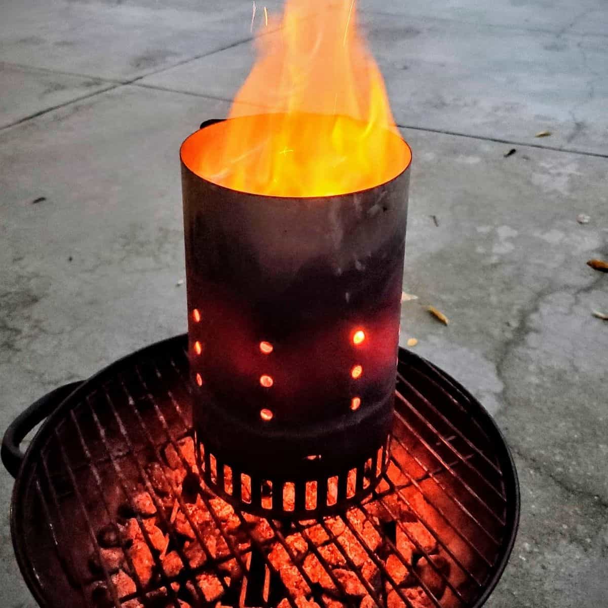 A charcoal chimney shown with a roaring flame. 