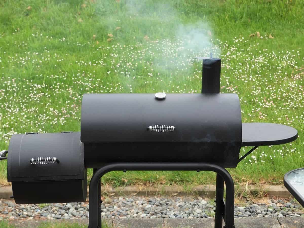 An offset smoker in a grassy field.