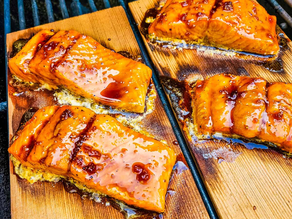 Salmon filets coated with a bourbon glaze being cooked on cedar planks.