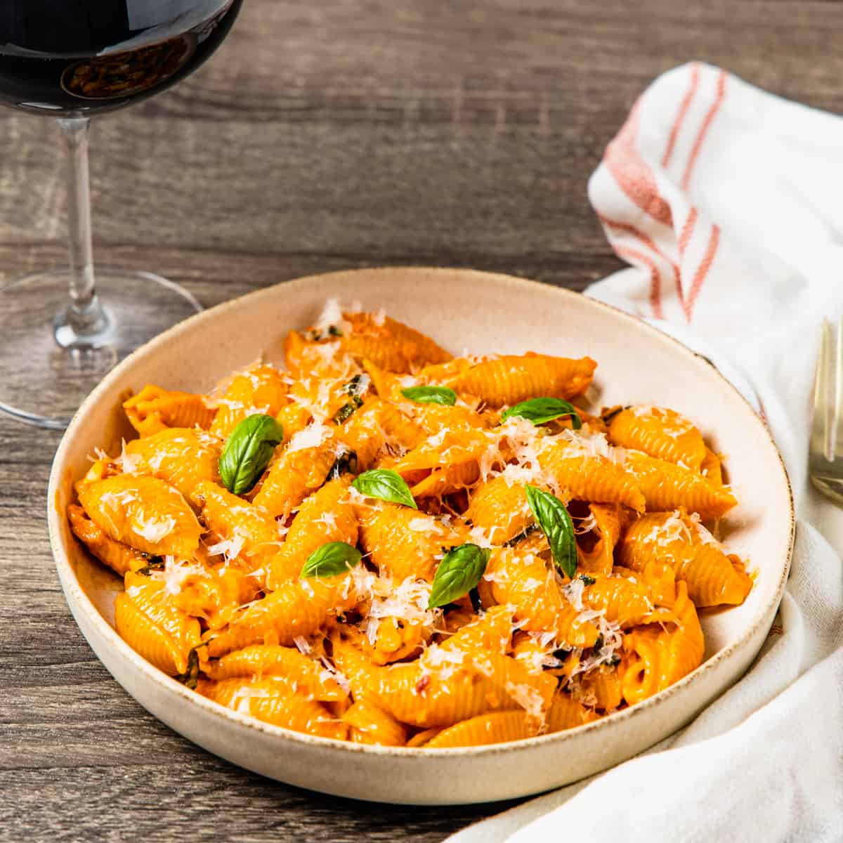 A large bowl of spicy pasta alla vodka served with a glass of red wine.