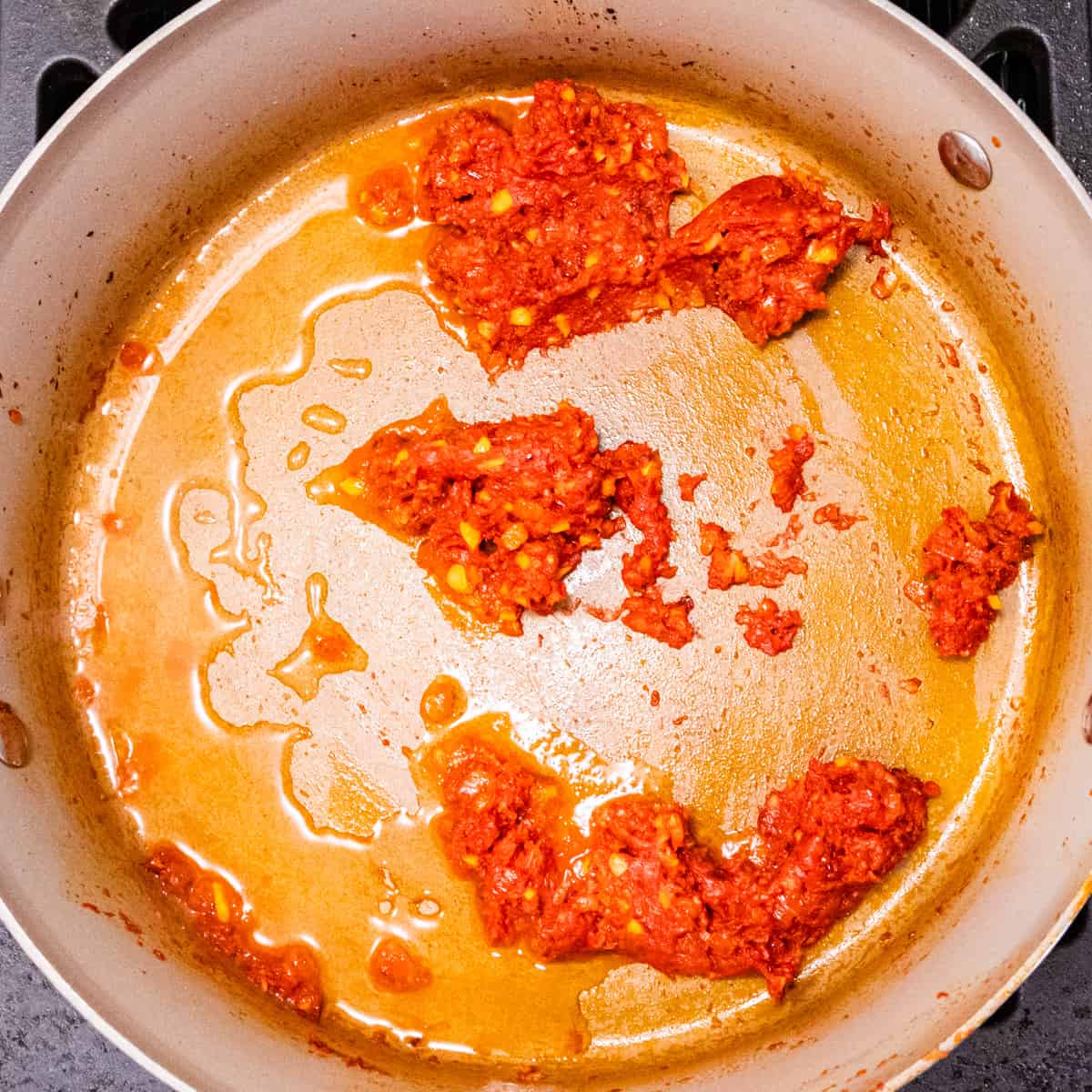 A saucepan with cooked tomato paste and vodka added to the pan. 