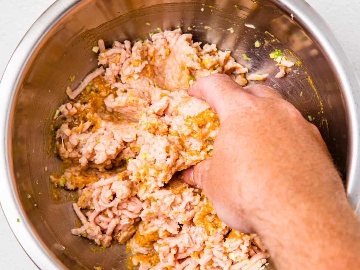 The meatball ingredients are shown in a mixing bowl being mixed by hand.