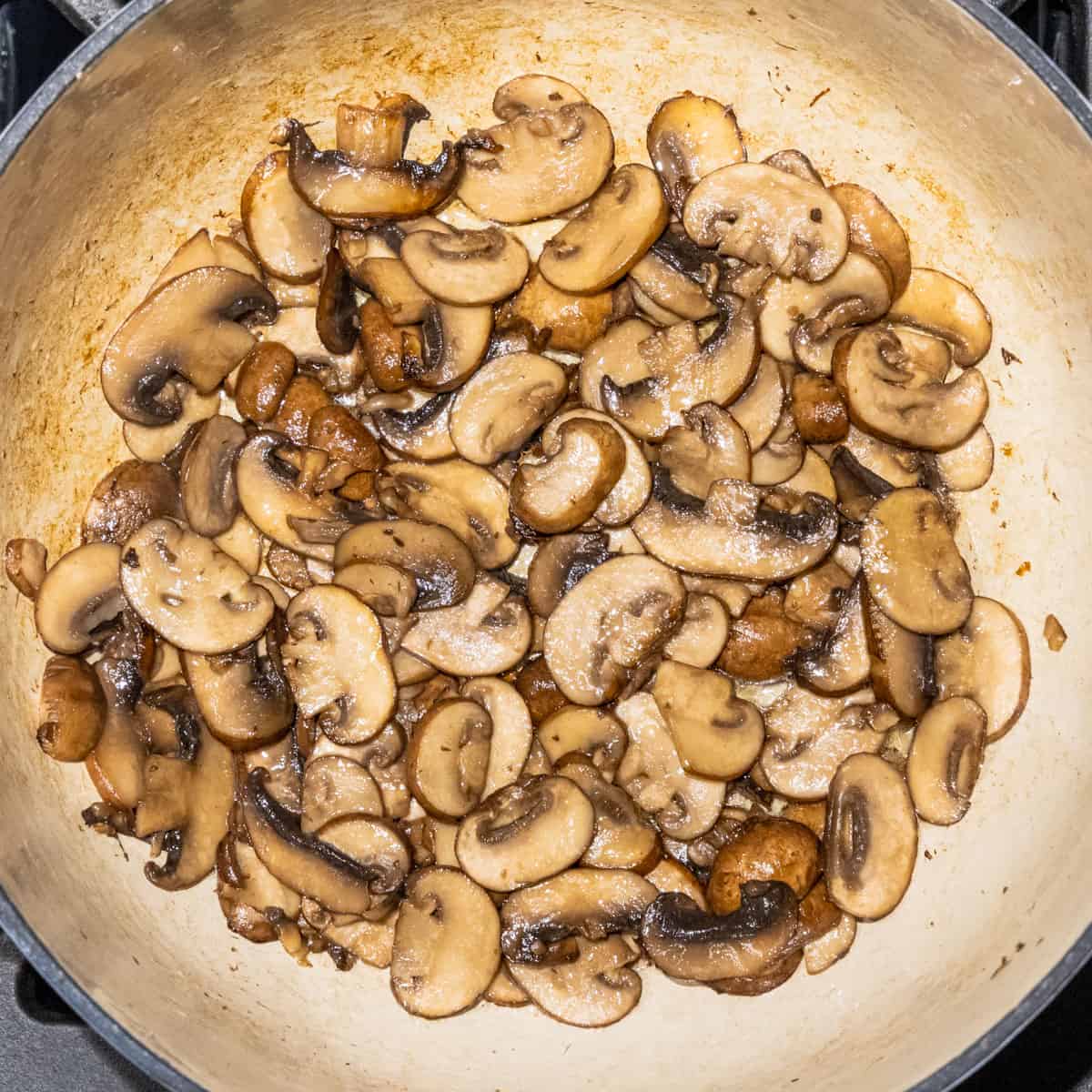 Mushrooms being cooked in a dutch oven.