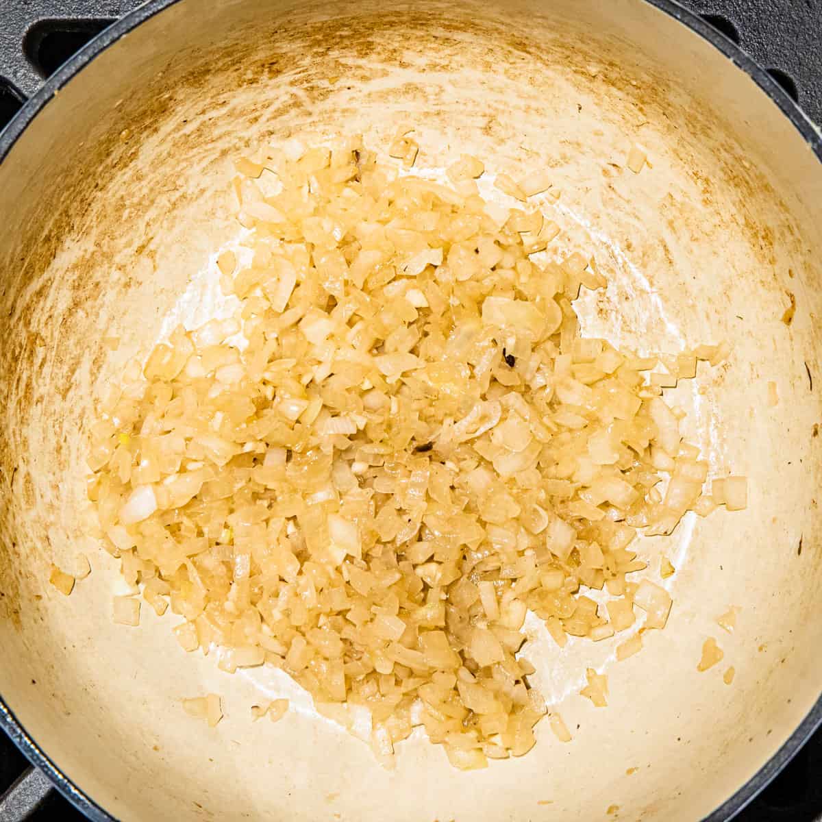 Diced onion being cooked in a dutch oven.