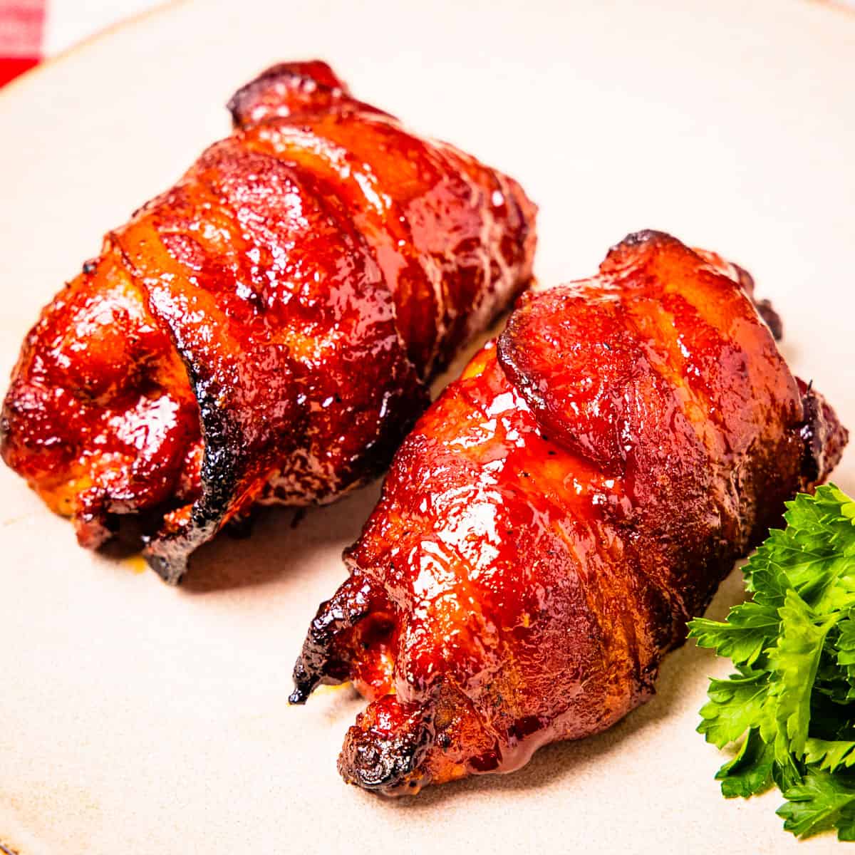 Smoked chicken thighs wrapped in bacon, shown served on a plate.