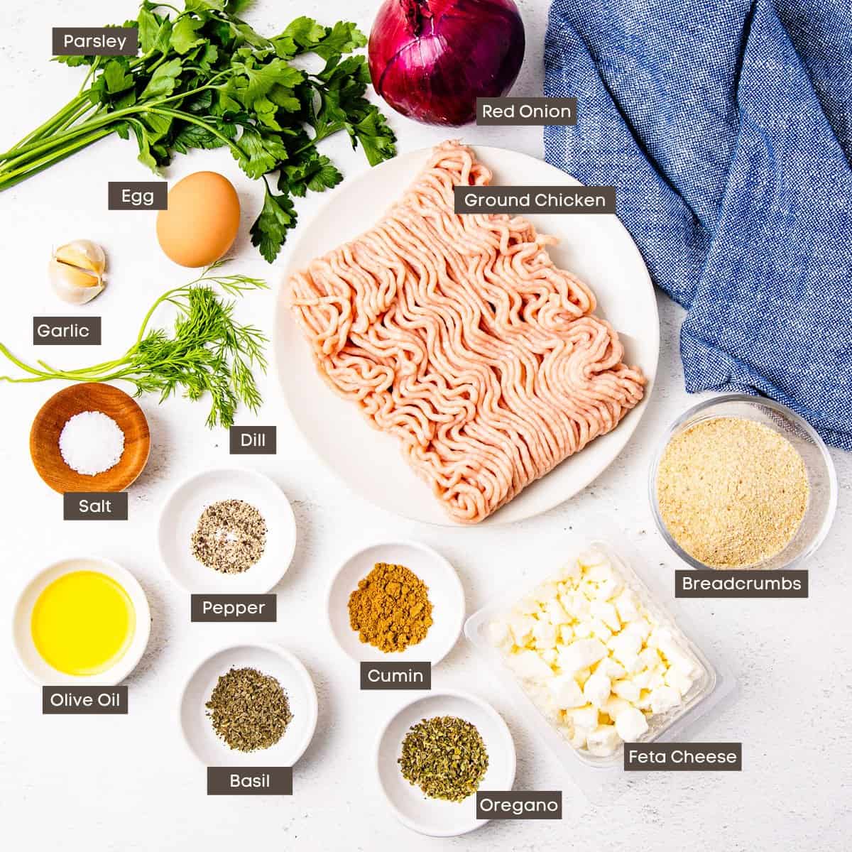 Ingredients for Greek chicken meatballs shown arranged on a counter in individual bowls. 