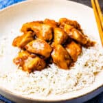 A serving of steamed rice topped with honey bourbon chicken.