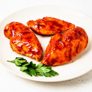 Barbecue chicken breasts on a serving plate.