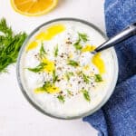 A bowl of homemade tzatziki sauce sitting on a countertop.