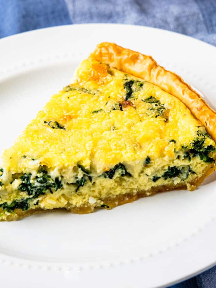 A slice of quiche Florentine on a white plate.