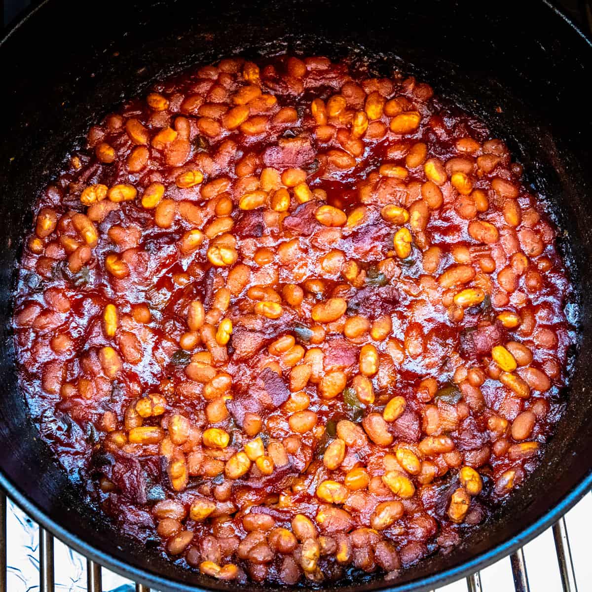 A large pot of smoked baked beans being cooked in a smoker.