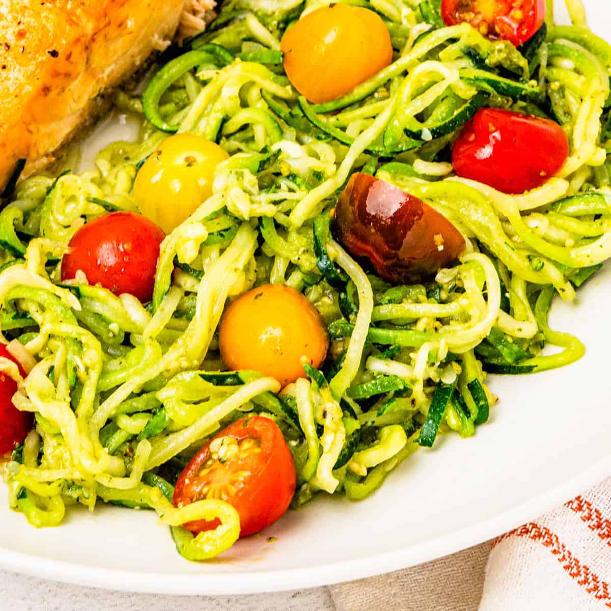 Zucchini noodles with pesto sauce and sliced cherry tomatoes.