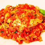 A pan-seared chicken cutlet smothered in fresh tomato sauce and served over spaghetti.