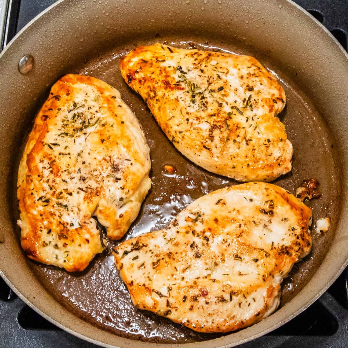 Chicken cutlets cooking in a pan.