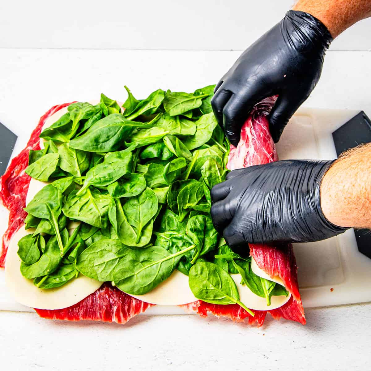 Steak pinwheel being rolled up on a cutting board. 