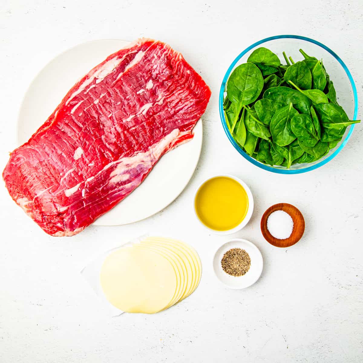 Ingredients for flank steak pinwheels shown arranged on a countertop.