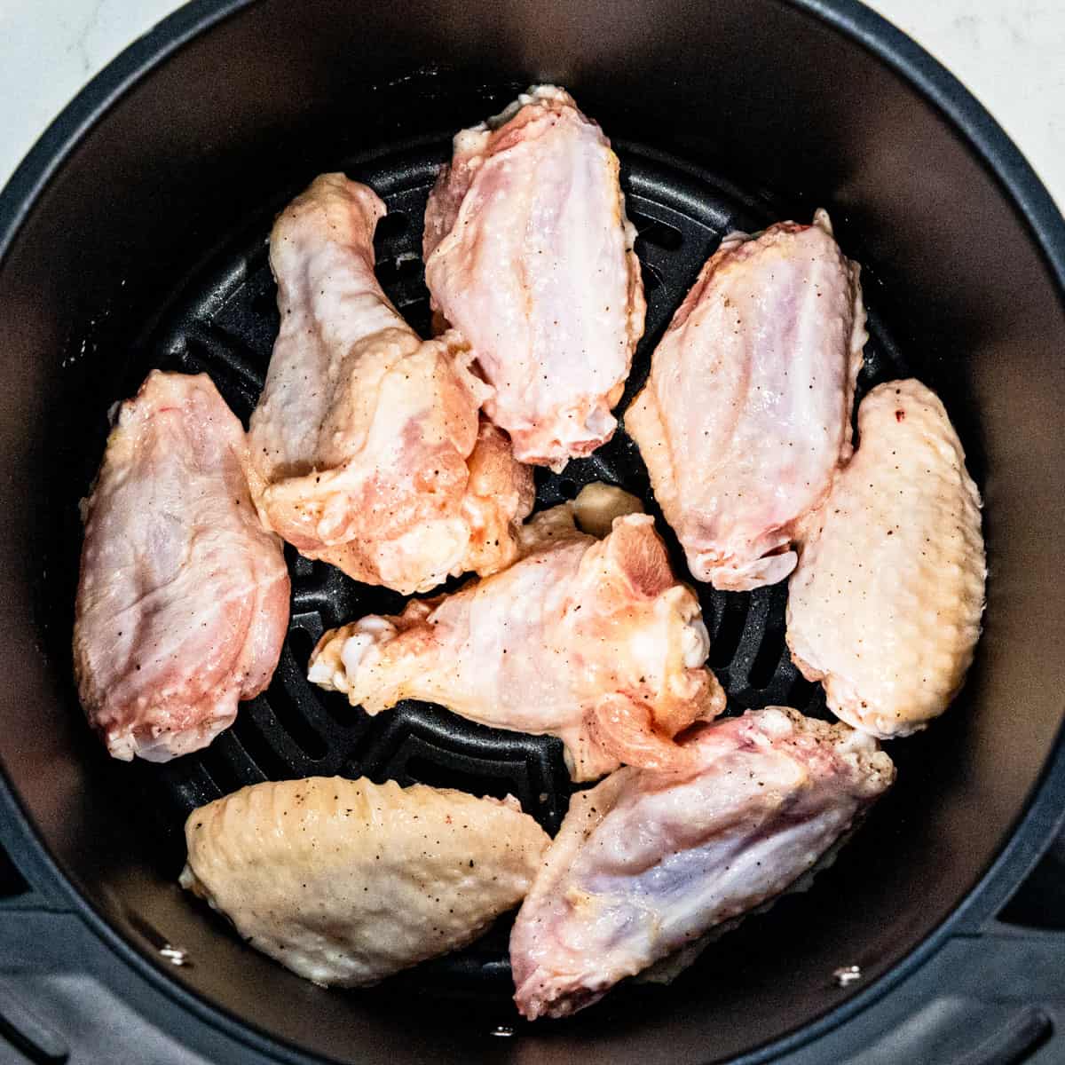 Chicken wings in an air fryer before cooking.