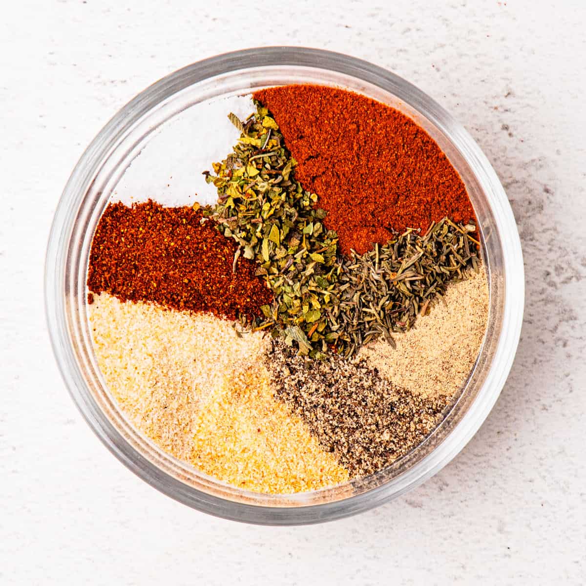 A variety of seasonings in a small bowl before being mixed together.