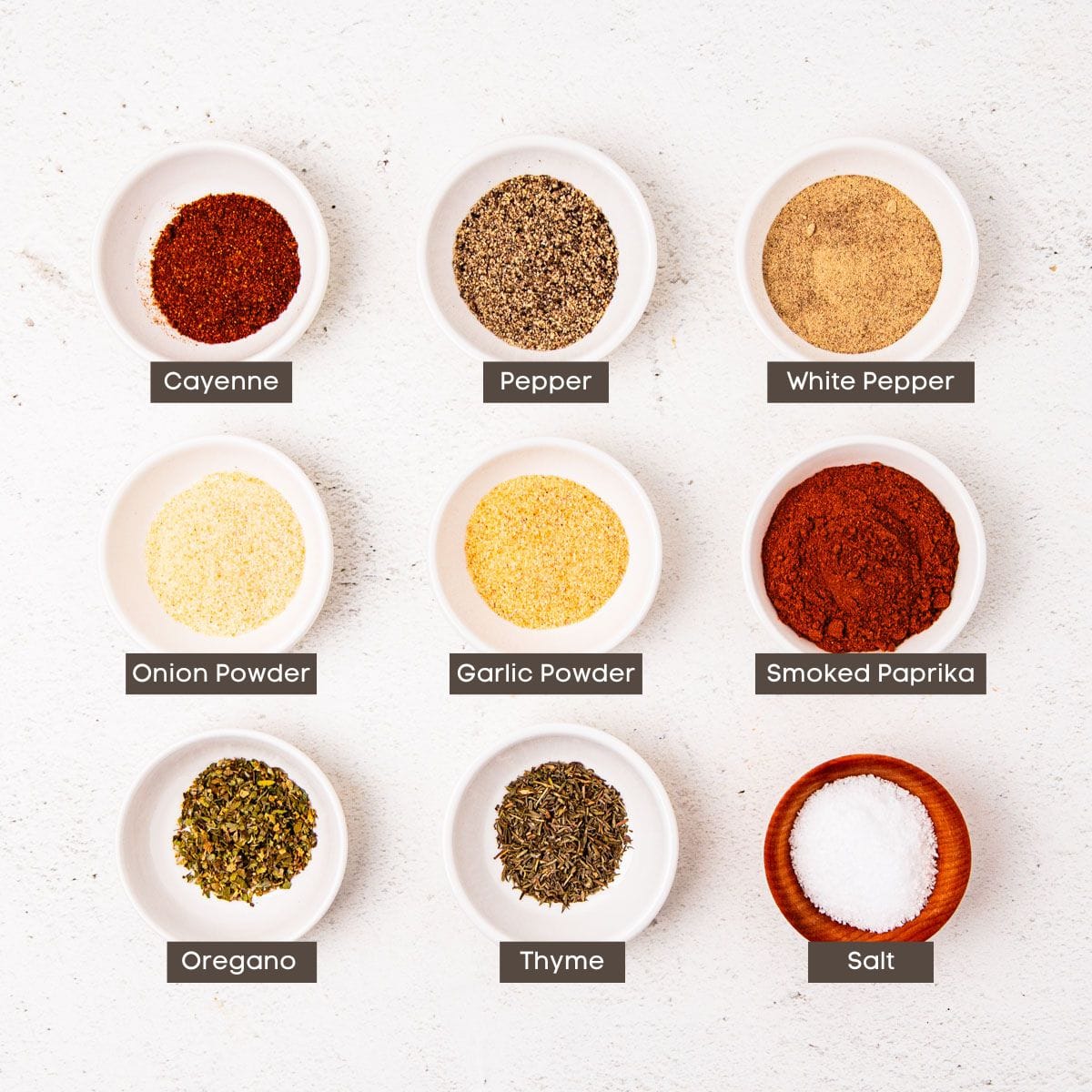 Ingredients for Creole seasoning in individual bowls on a countertop.