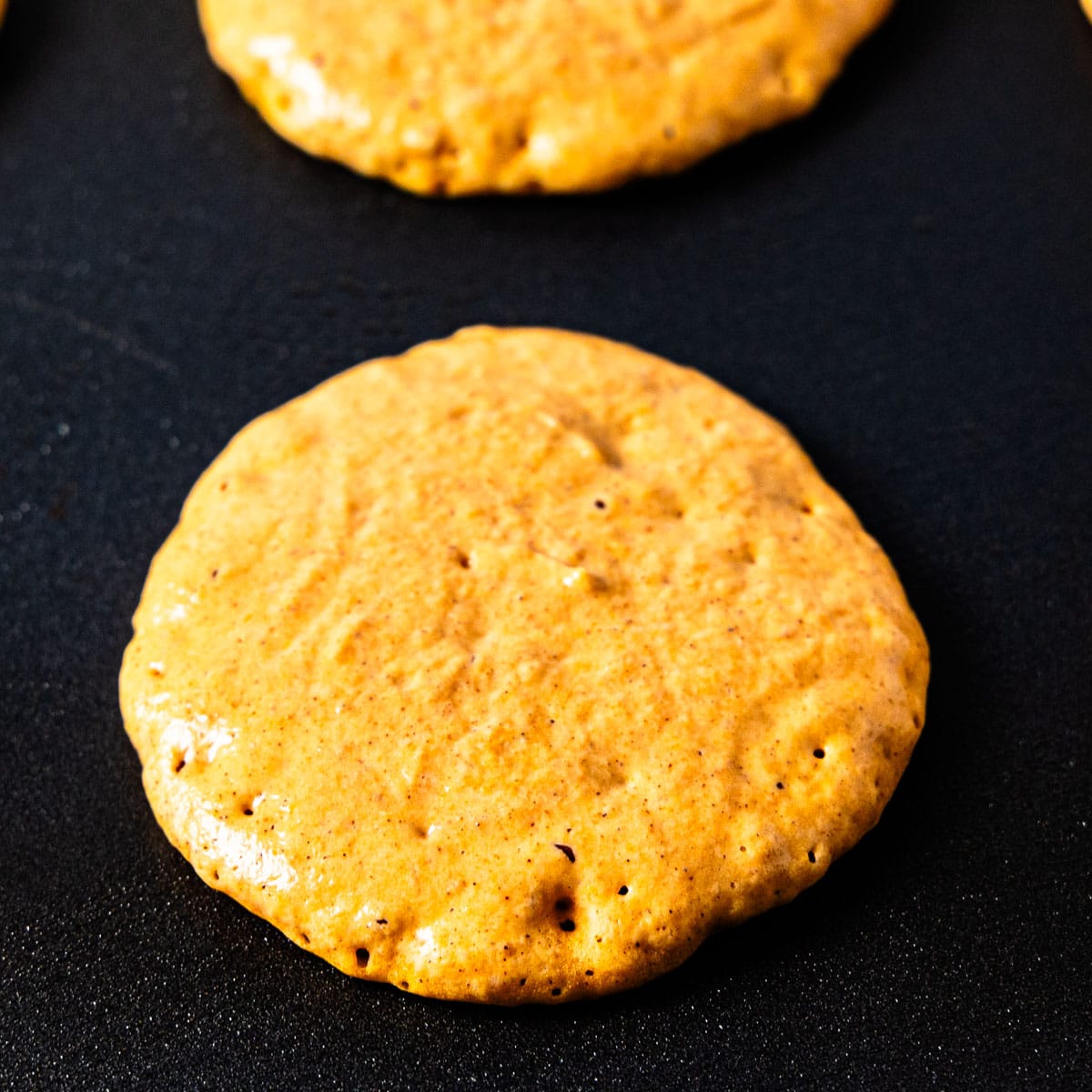 Pumpkin pancake cooking on a griddle.